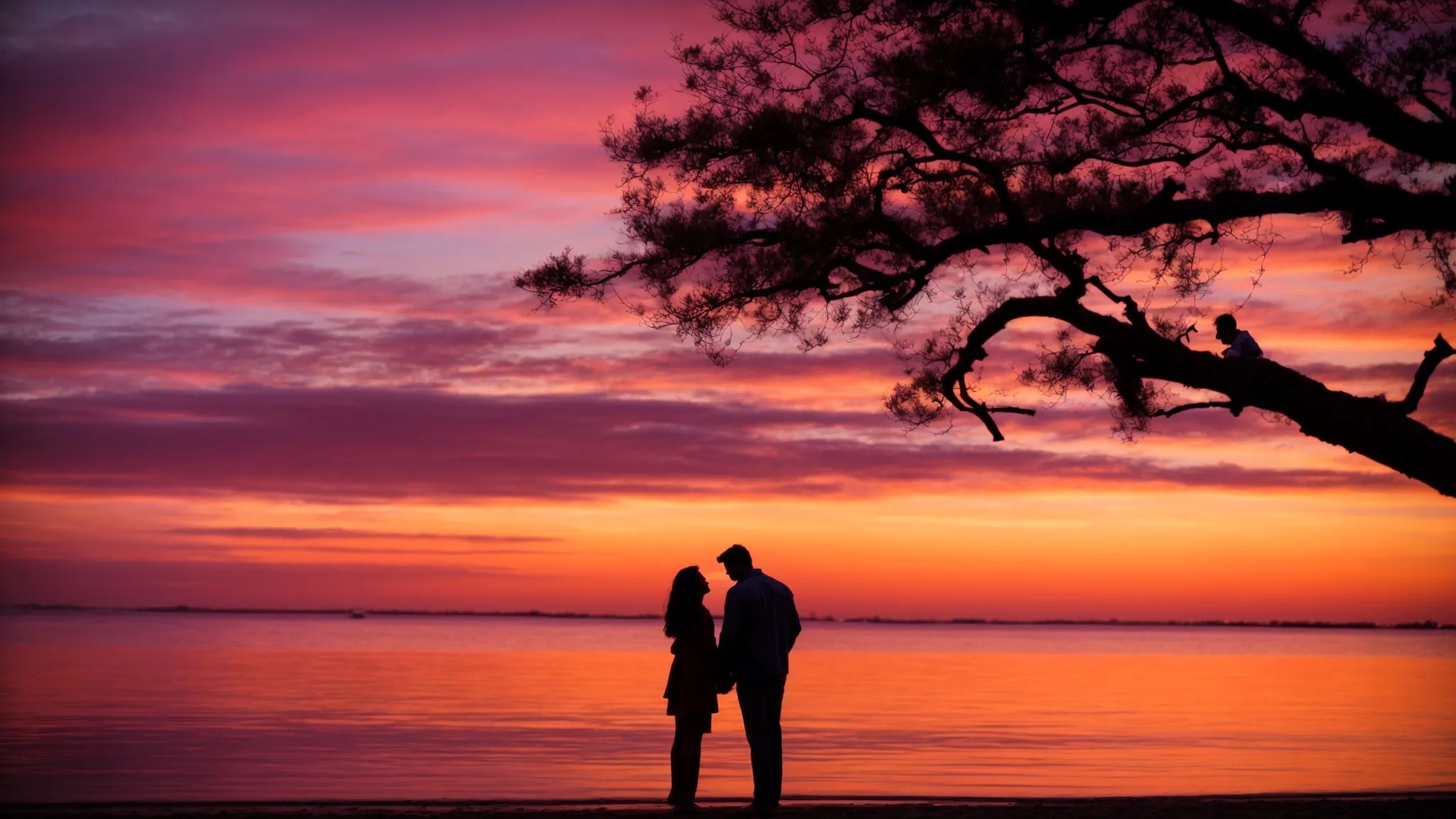 a couple embraces gently on a serene beach at sunset, their silhouettes framed by the vibrant colors of the sky reflecting on the water.