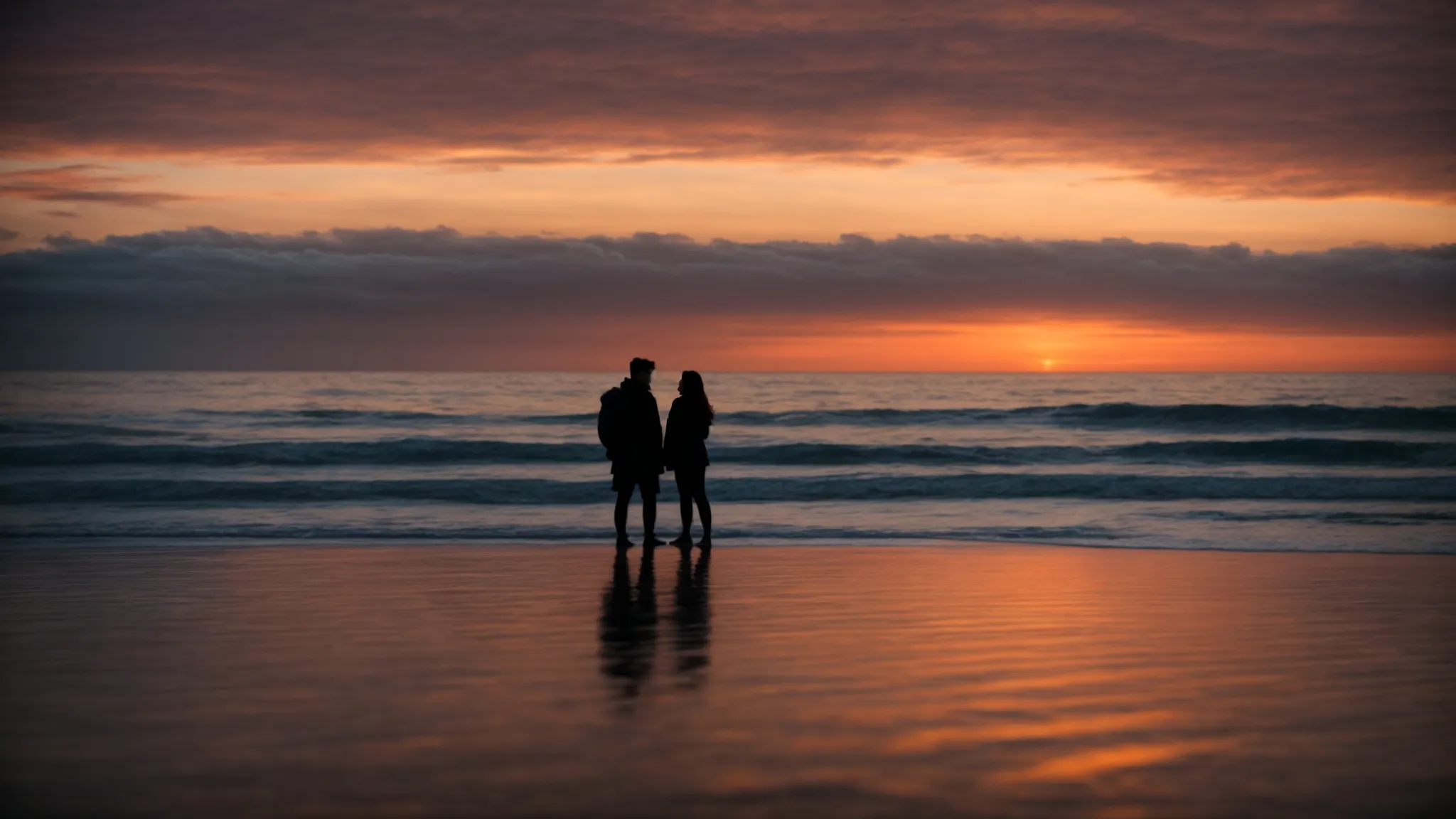 a couple shares a quiet moment together, silhouetted against a breathtaking sunset by the sea.