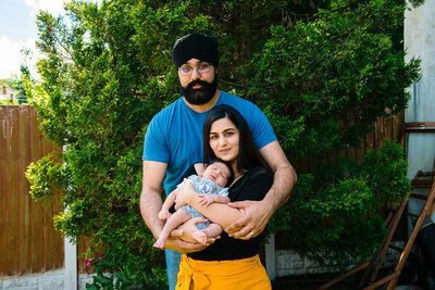 Parents holding their newborn together in a garden