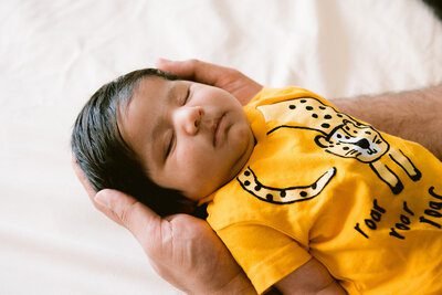 A sleeping newborn in a yellow outfit