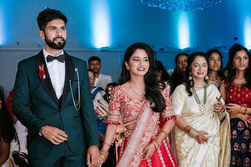 Couple standing together at their engagement celebration in a green suit and coral lehenga