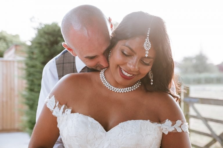 Groom embracing his smiling bride during an outdoor wedding portrait