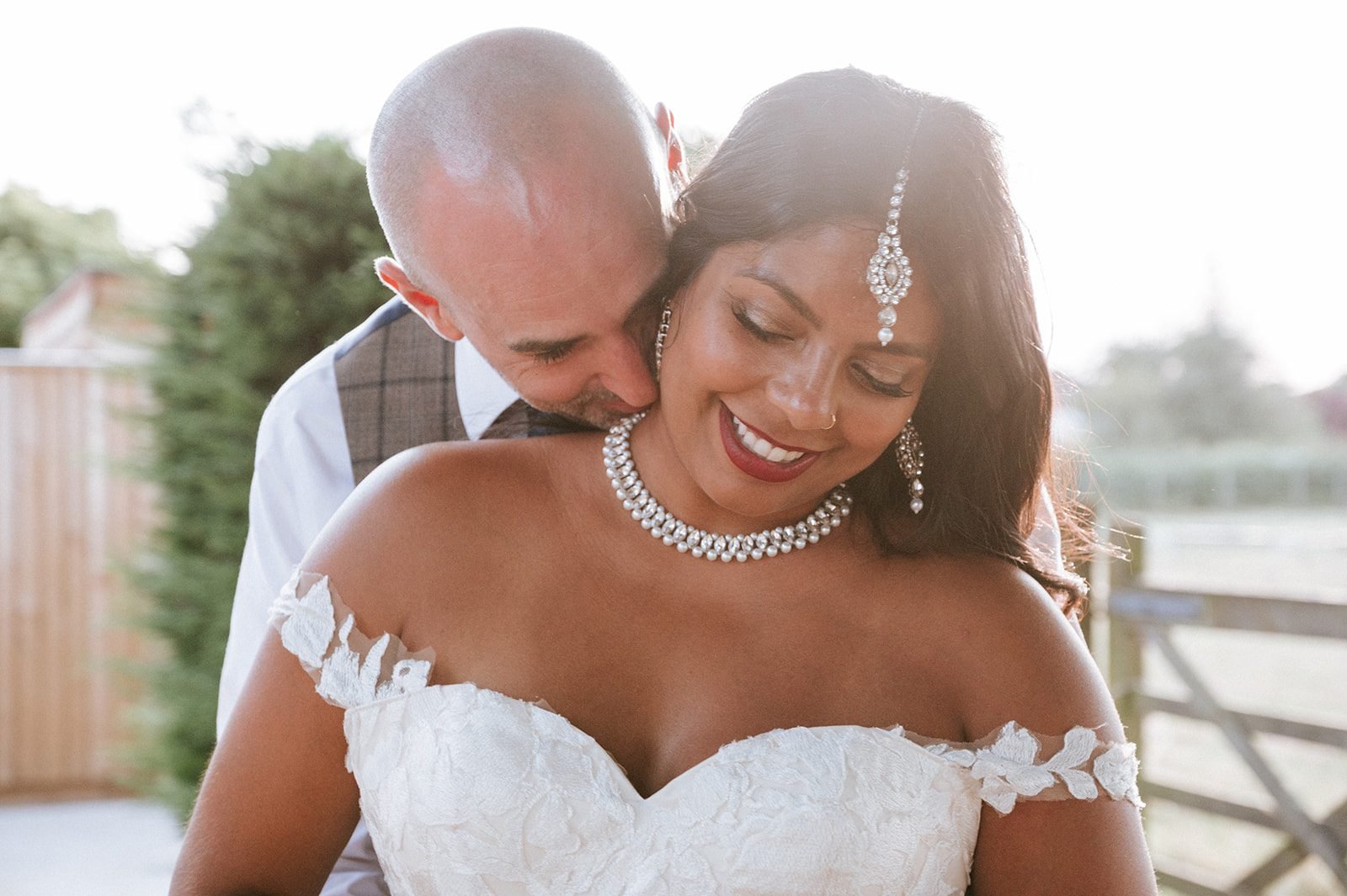 Groom embracing his smiling bride during an outdoor wedding portrait