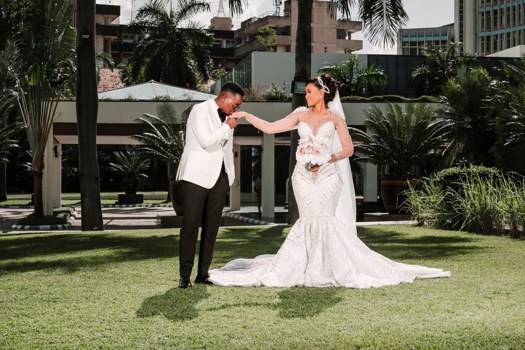 Bride and groom holding hands on a sunlit lawn