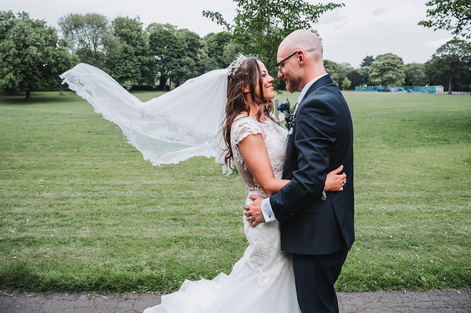 Kerry and Liam embracing outdoors as the bride’s veil lifts in the breeze