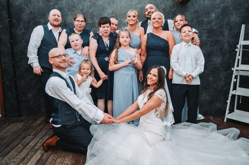 Bride sitting with the groom and a group of family and friends