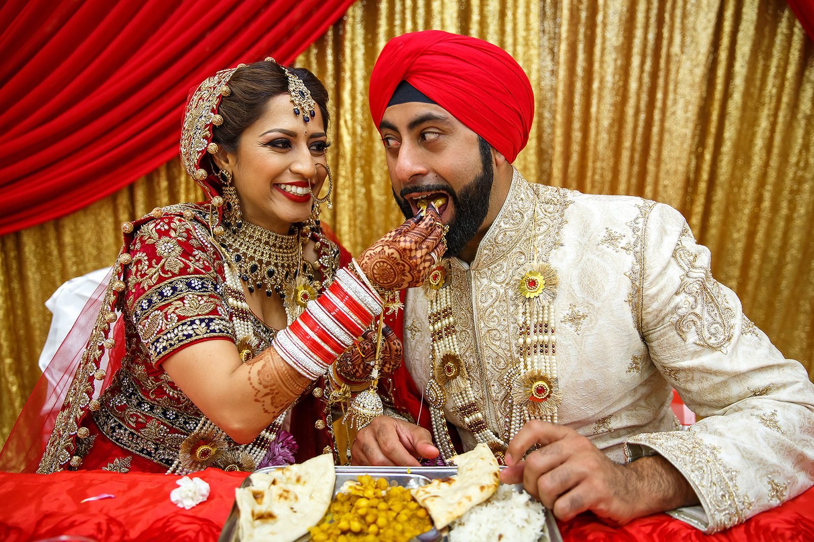 Sikh bride and groom sharing food during their wedding celebration