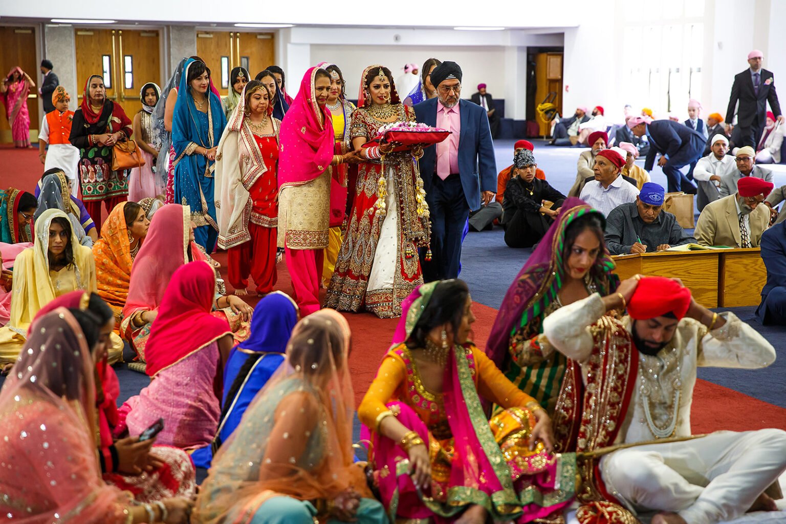 Wide view of a Sikh bride and groom bowing during their Anand Karaj