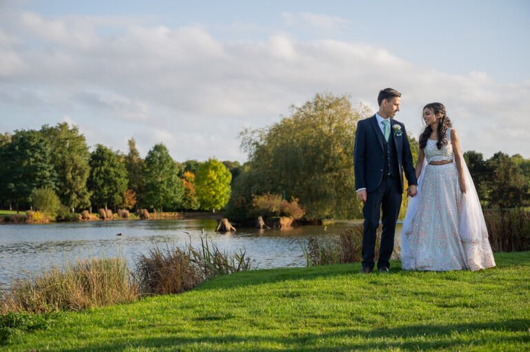 Bride and groom standing beside a lake for their wedding portraits