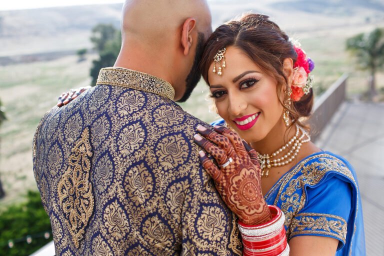 Bride in blue wedding attire smiling beside her groom