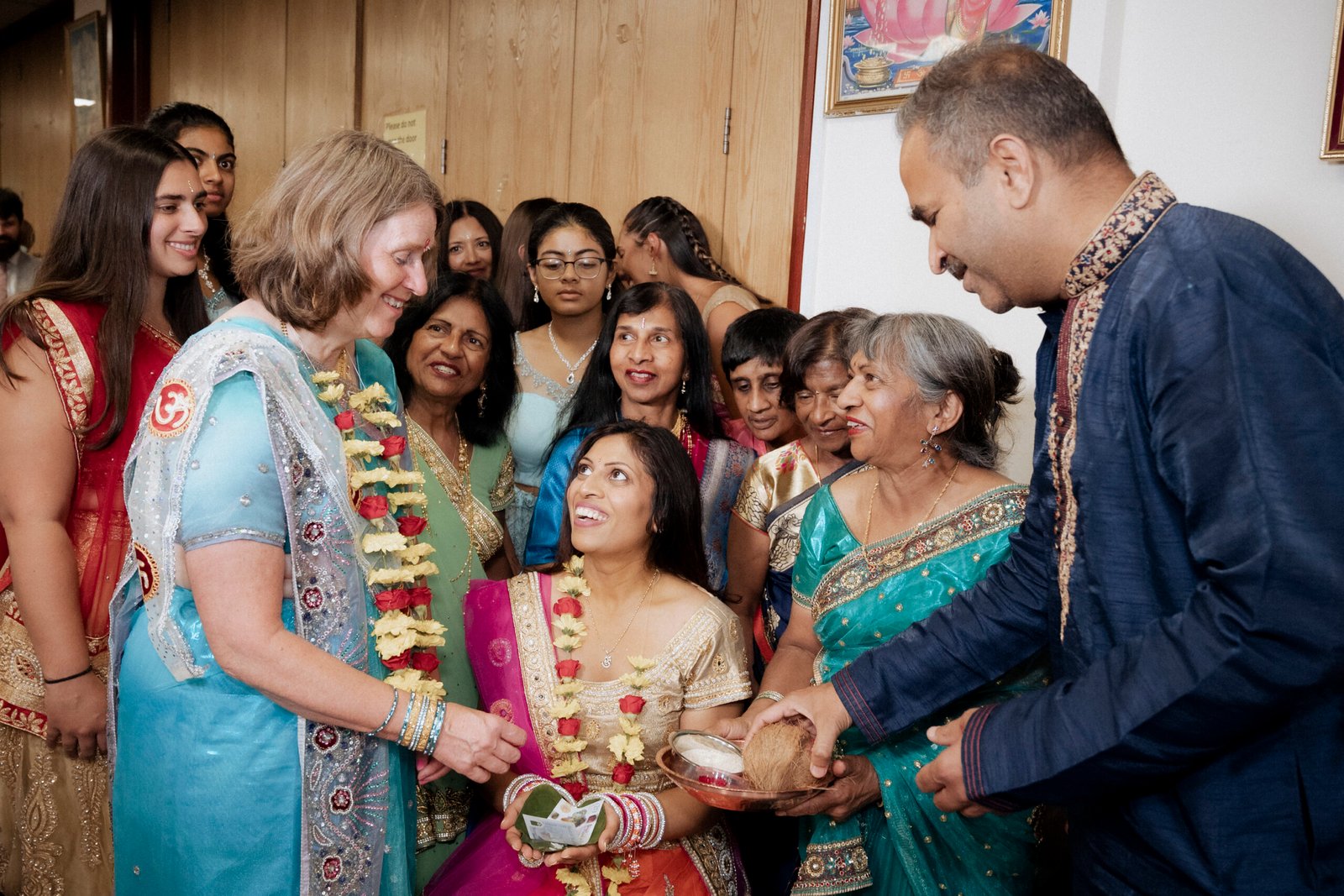 Family members wearing fresh rose and marigold garlands seated together for blessings during a Gujarati Mandvo ceremony in Birmingham, photographed by Ikonic Media Solutions
