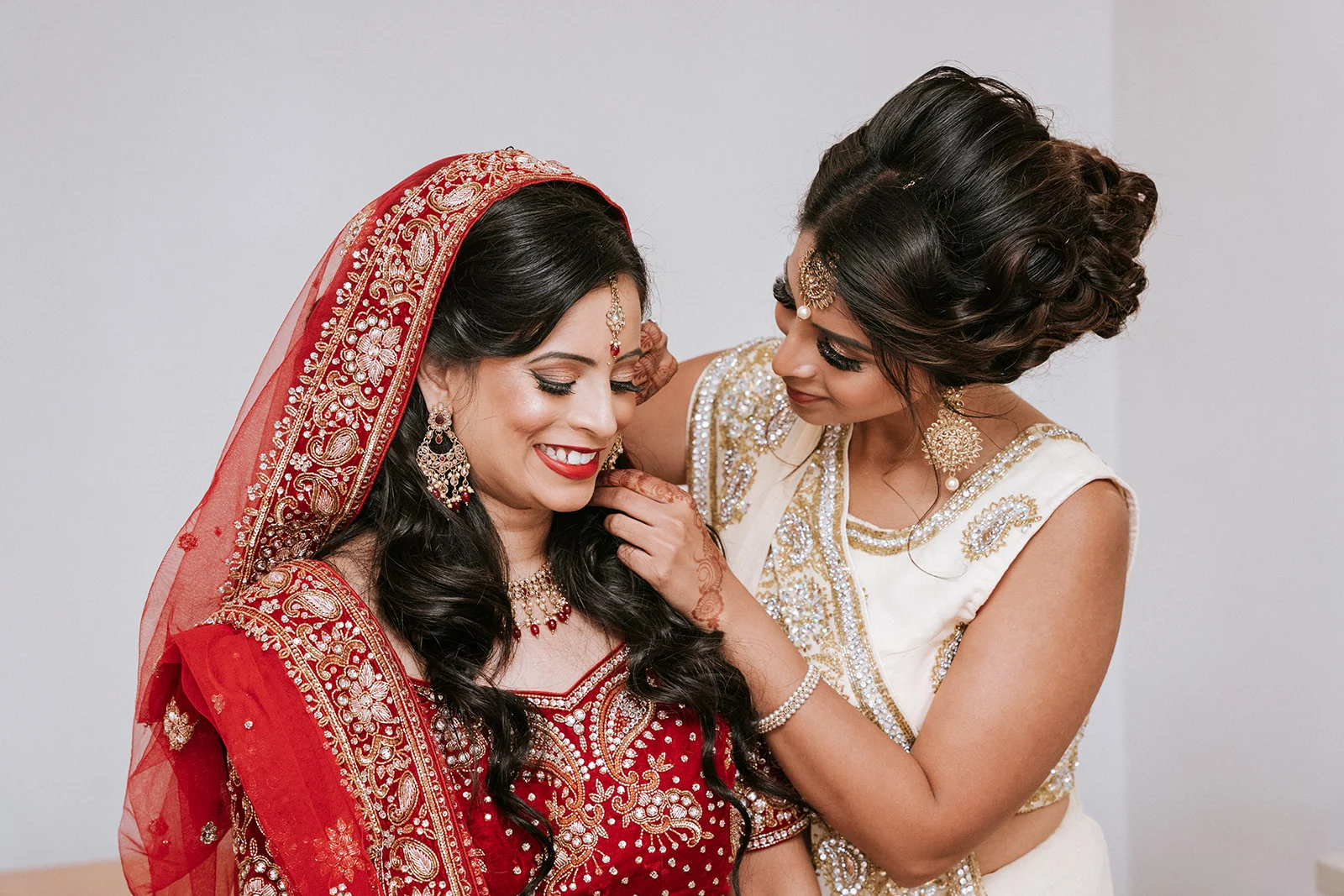 Asian bride helped with her jewellery before the wedding ceremony