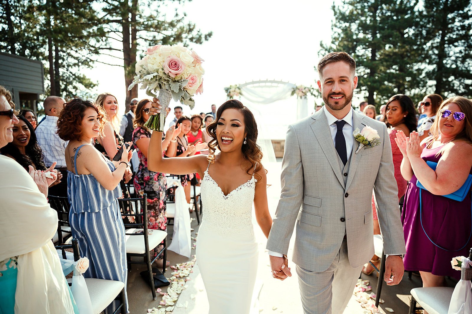 Newly married couple walking hand in hand past guests at an outdoor ceremony
