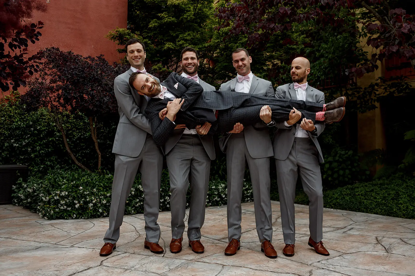 Groomsmen holding the smiling groom horizontally before the wedding