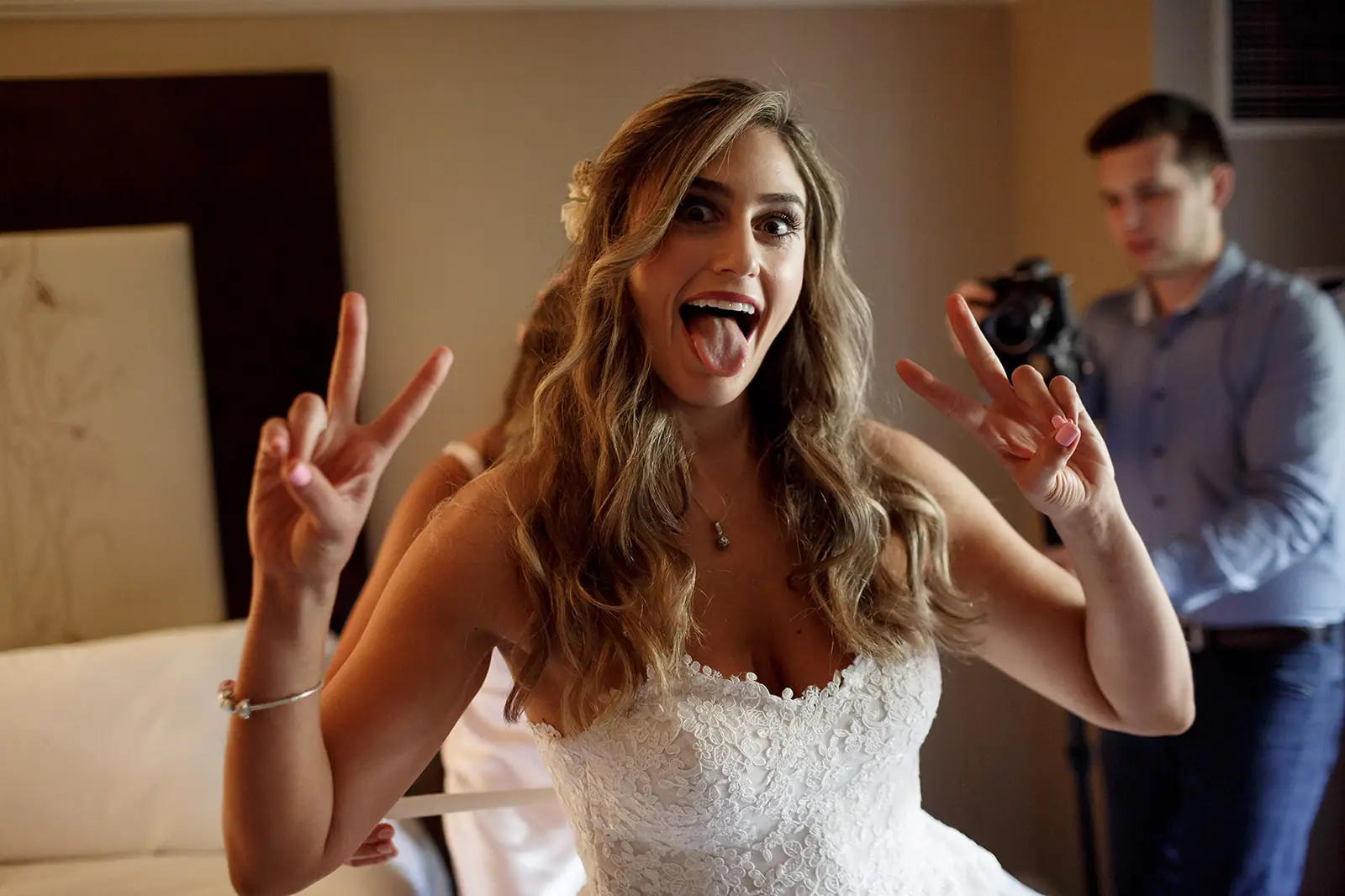 Bride making a playful face and peace signs in her wedding dress