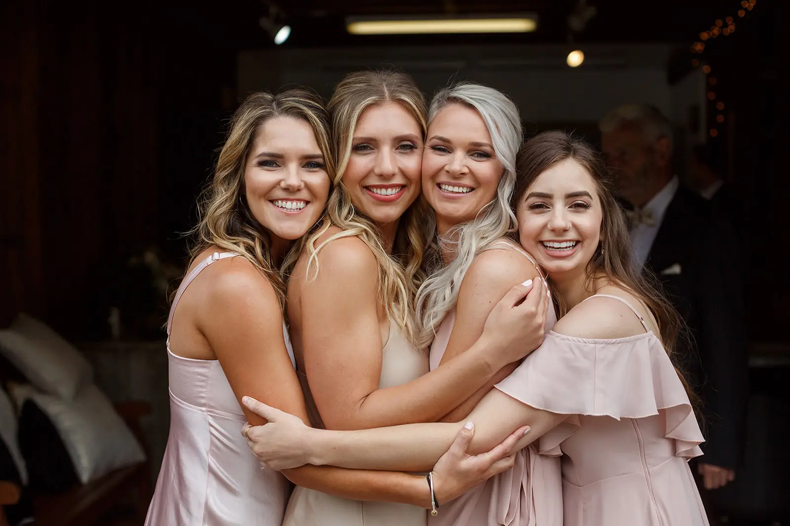 Bride embracing three bridesmaids in blush dresses