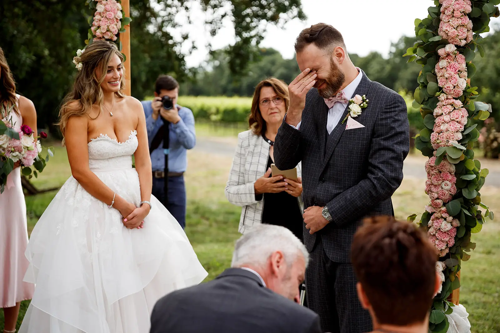 Groom covering his eyes during an emotional outdoor wedding ceremony