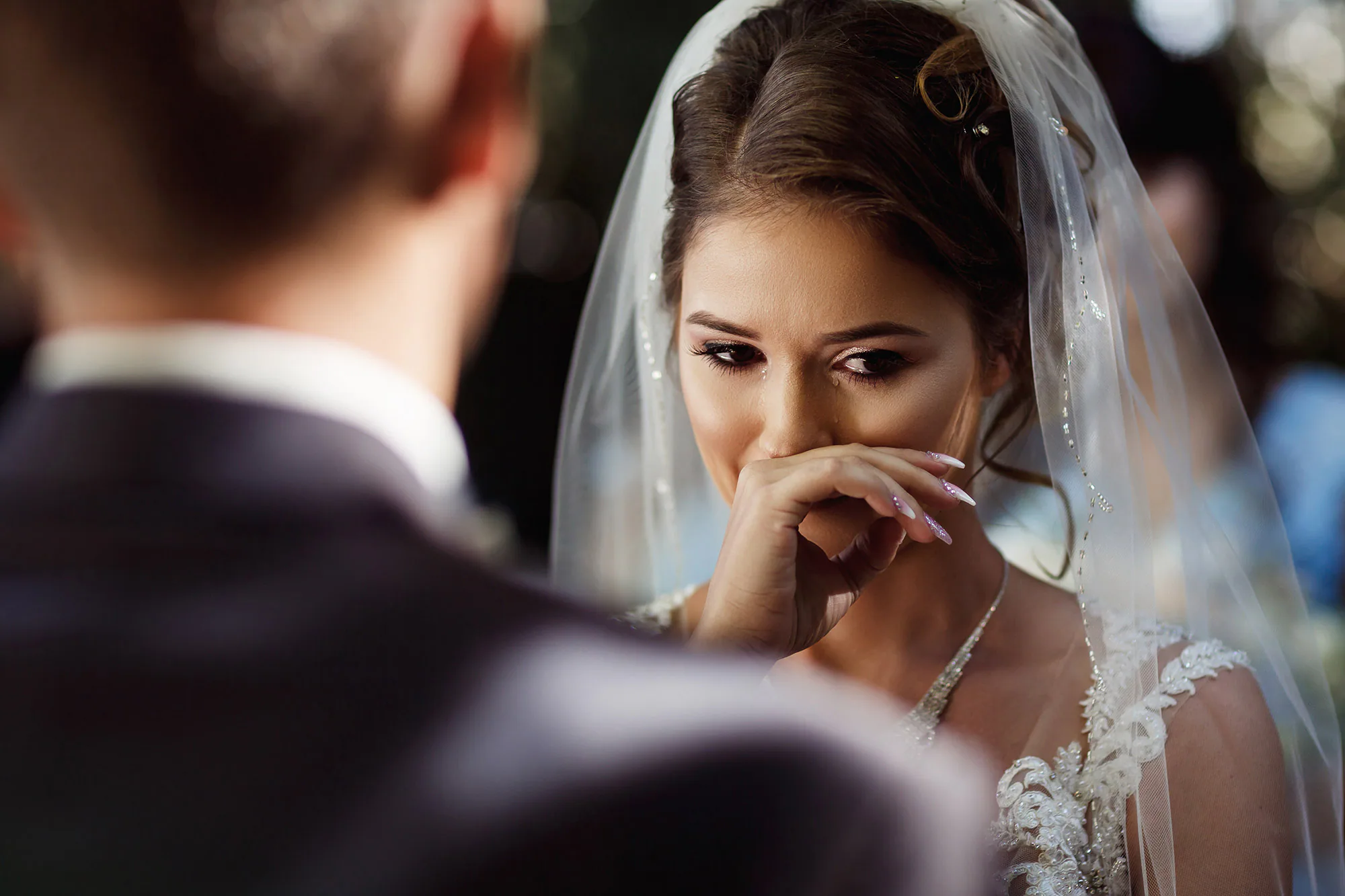 Emotional bride wiping away a tear during her wedding ceremony