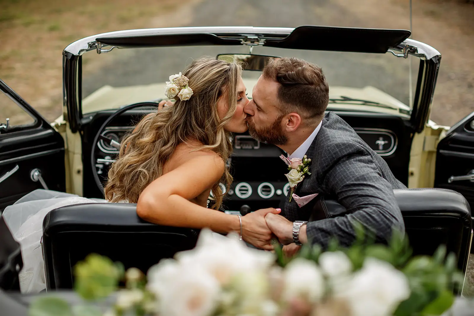 Newlyweds kissing in an open-top wedding car