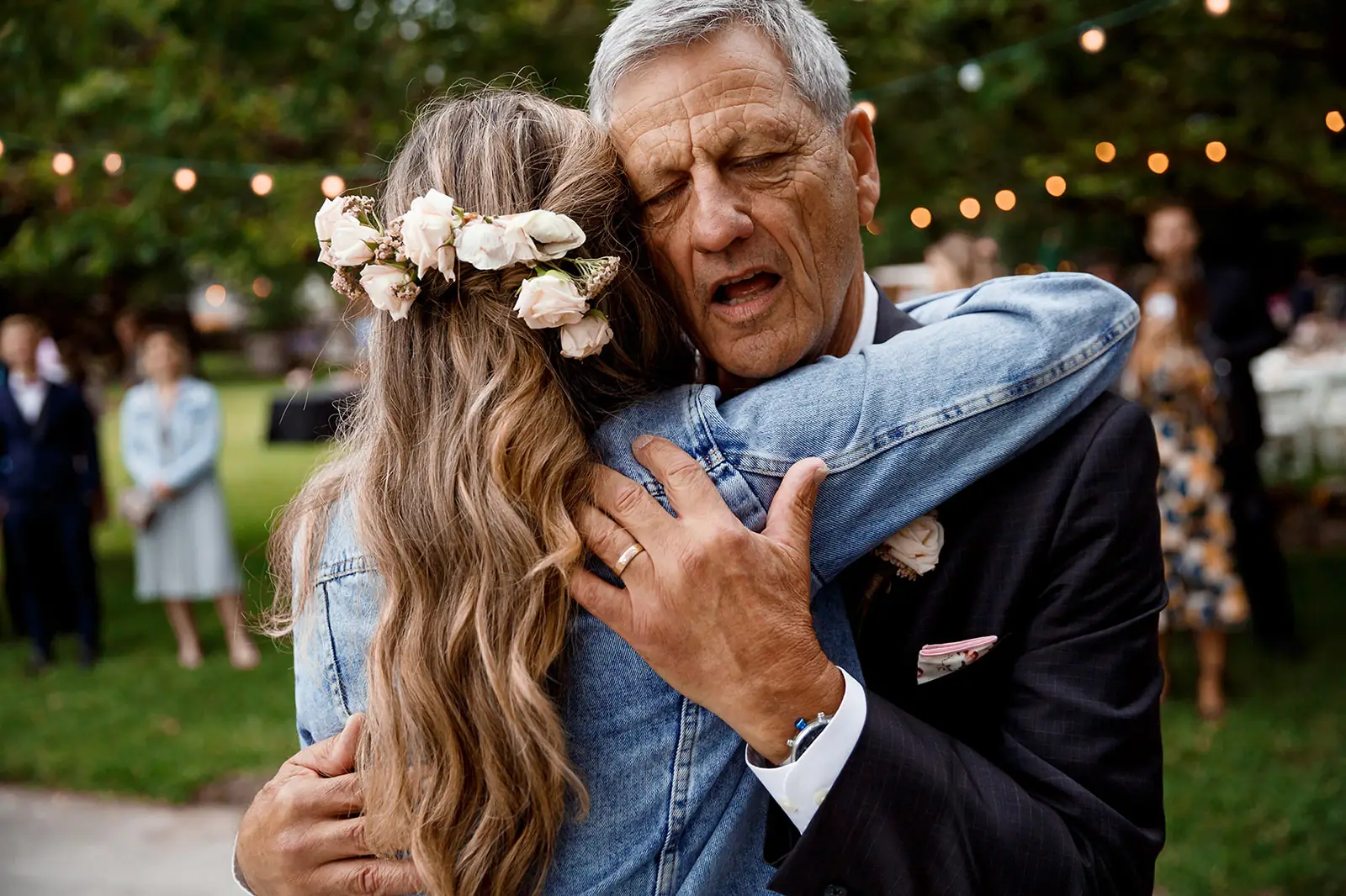 Older wedding guest embracing a woman in a denim jacket