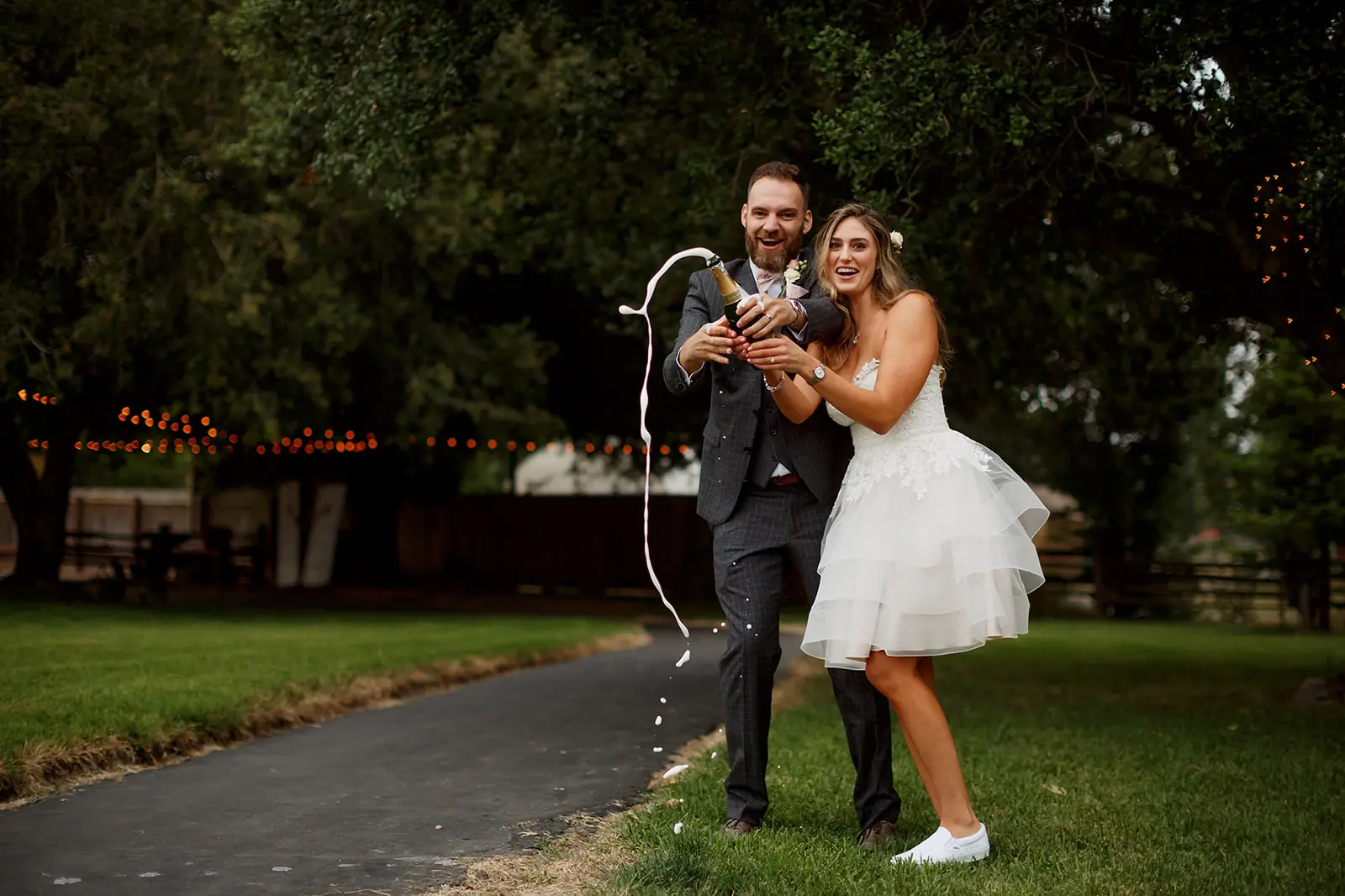 Bride and groom opening champagne in the garden at their wedding