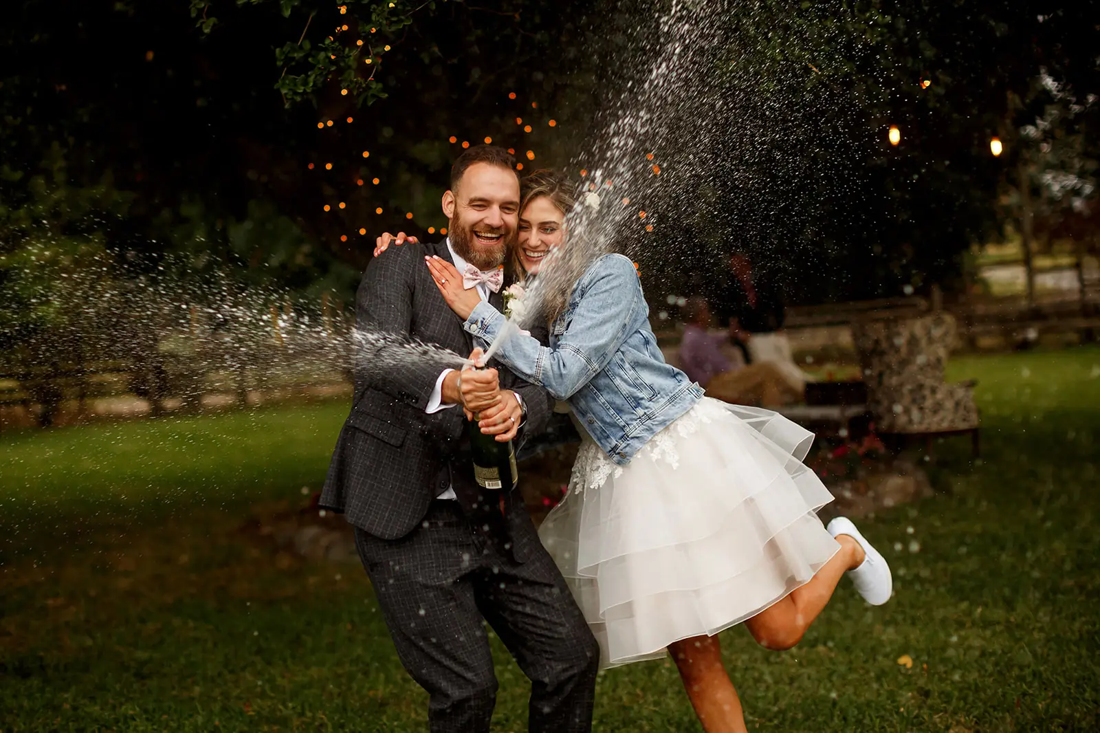 newlyweds laughing as they spray champagne at their wedding reception