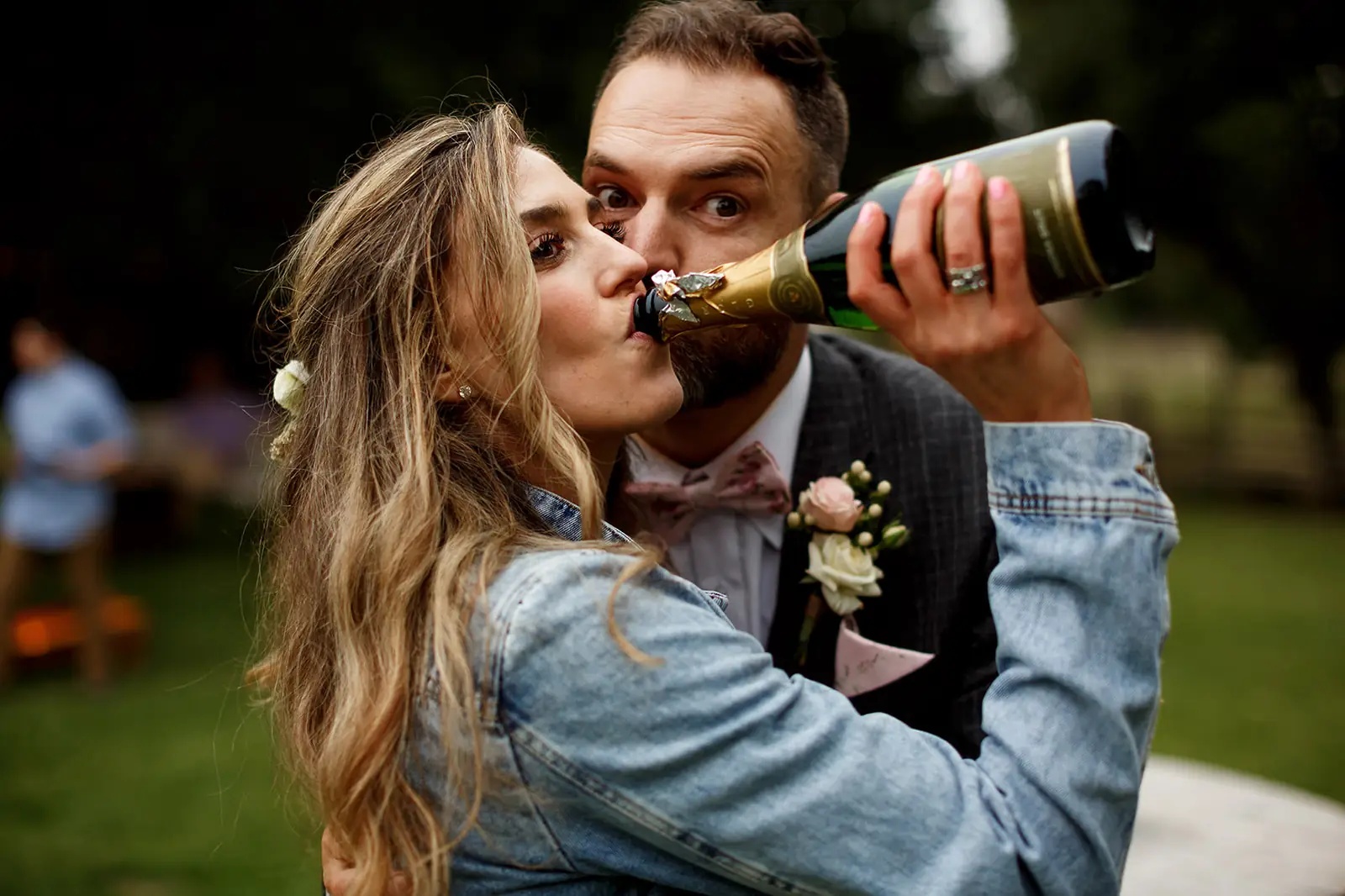Playful newlywed couple sharing champagne after their ceremony