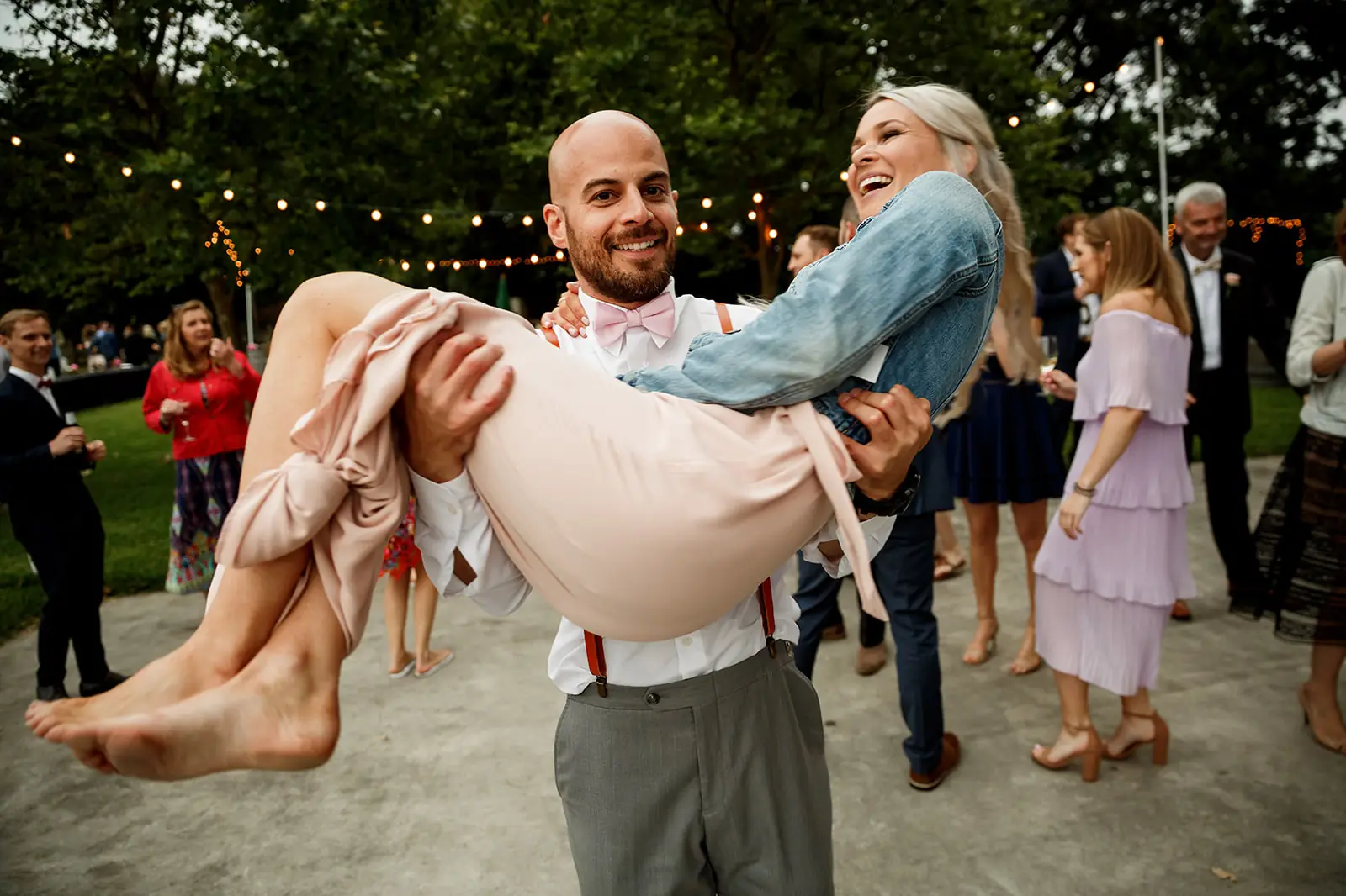 Wedding guest laughing as a groomsman lifts her on the dance floor