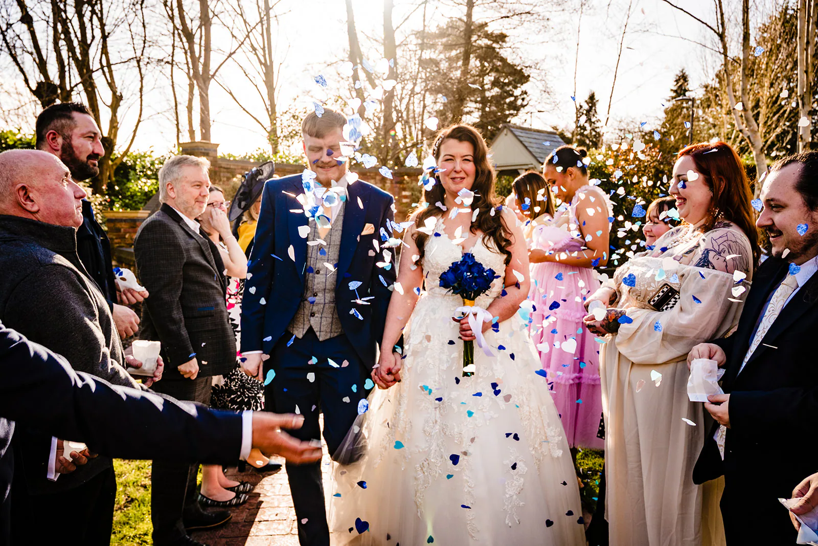 Newly married couple walking through blue and white confetti after their ceremony