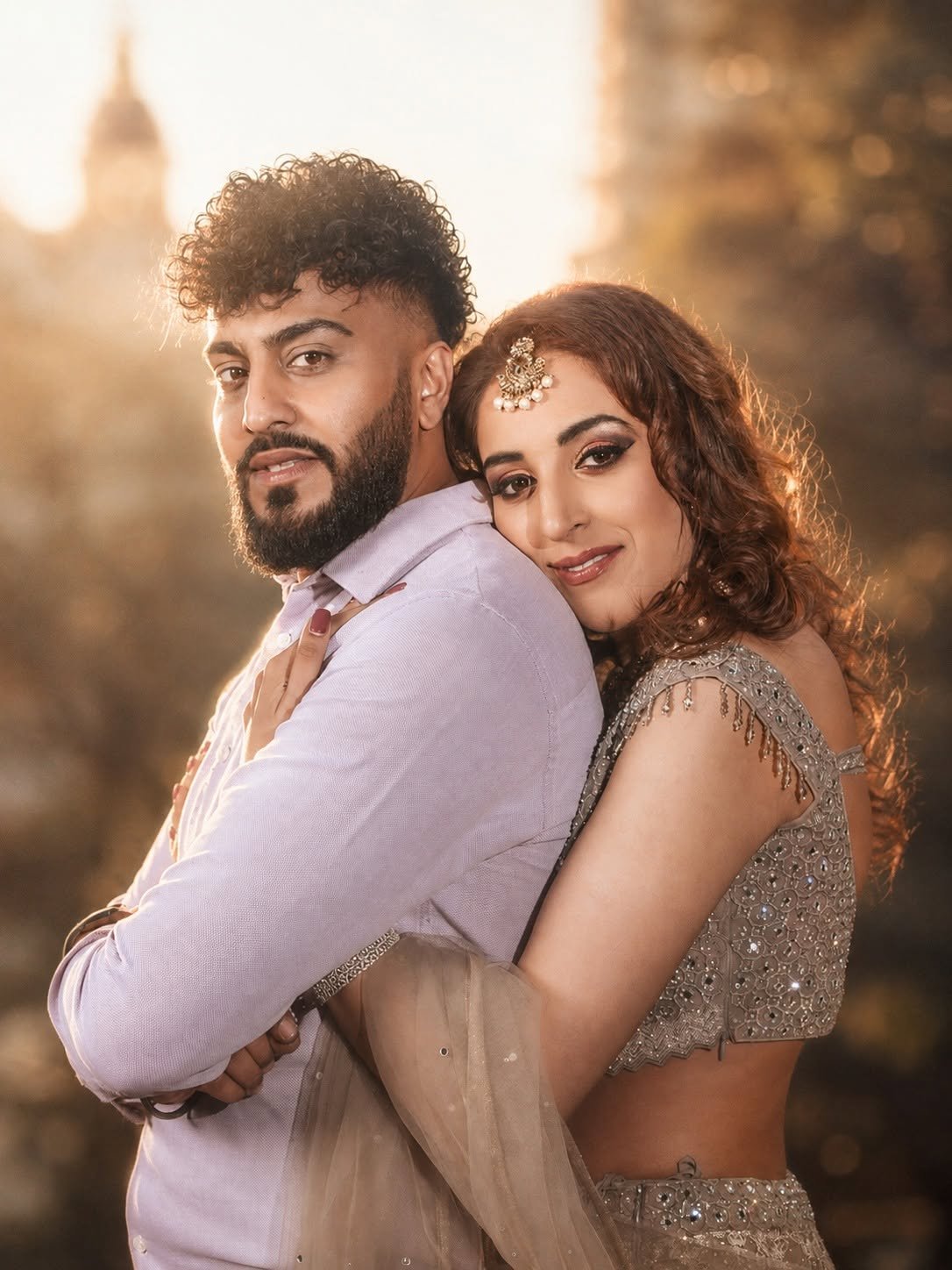 Couple embracing in warm sunlight, wearing lilac and embroidered champagne outfits