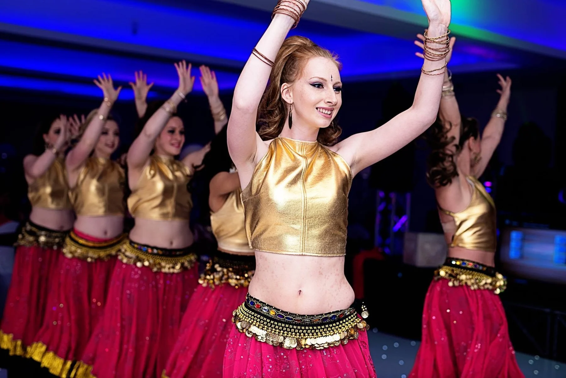 Dance performers in gold and pink costumes at a wedding reception