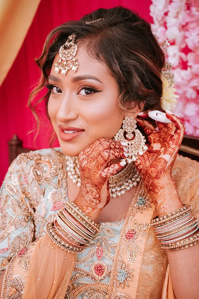 Asian bride adjusting her earrings before her wedding ceremony