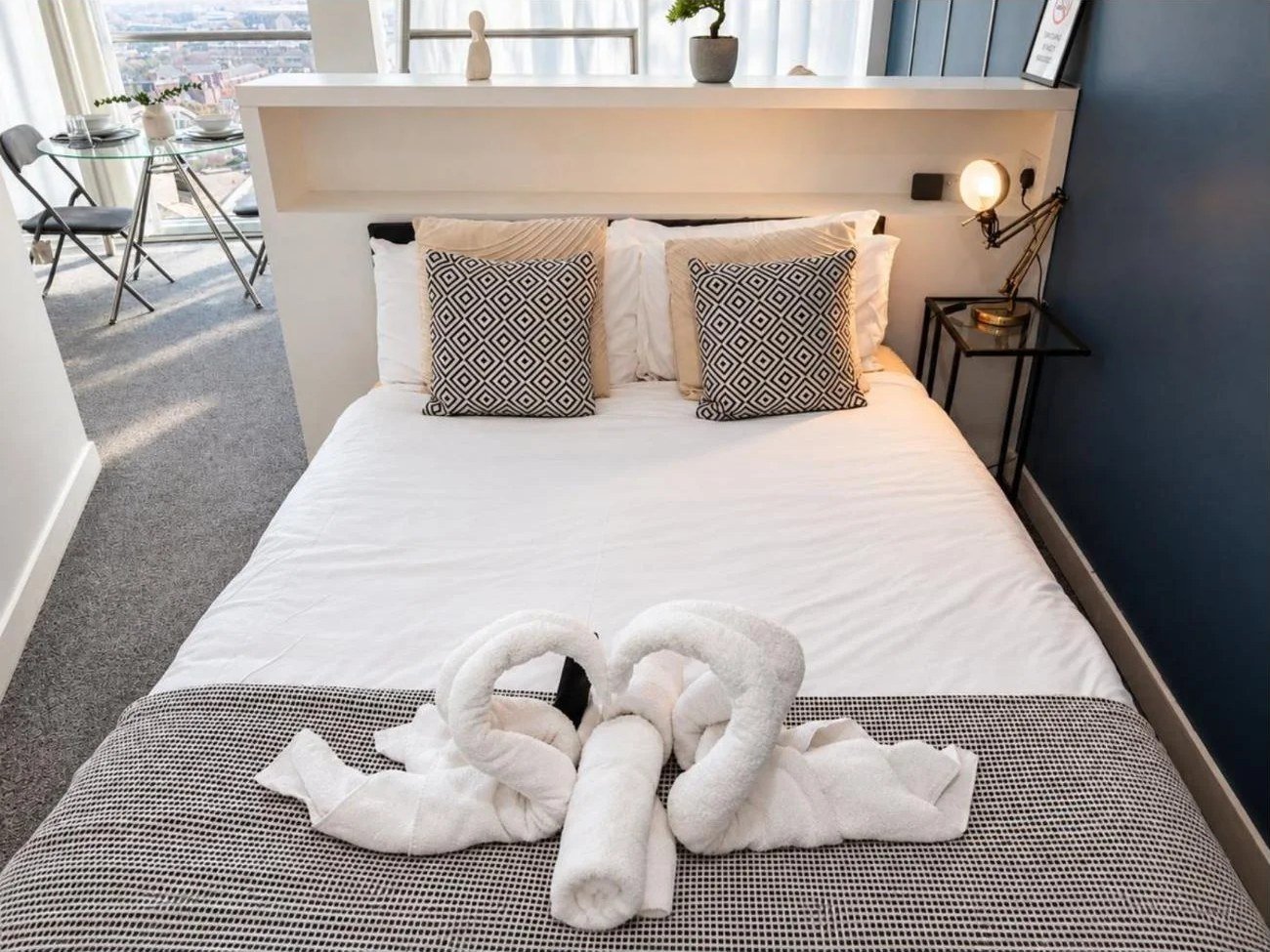 Airbnb bedroom photography in Birmingham: hotel-style double bed with towel swans and patterned cushions