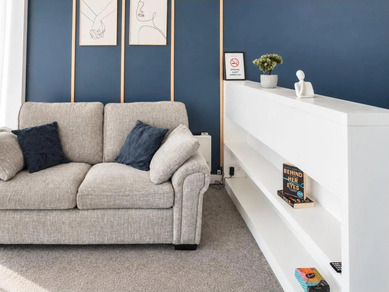 Holiday let photography Birmingham: navy feature wall, line-art prints, sofa and white shelving unit