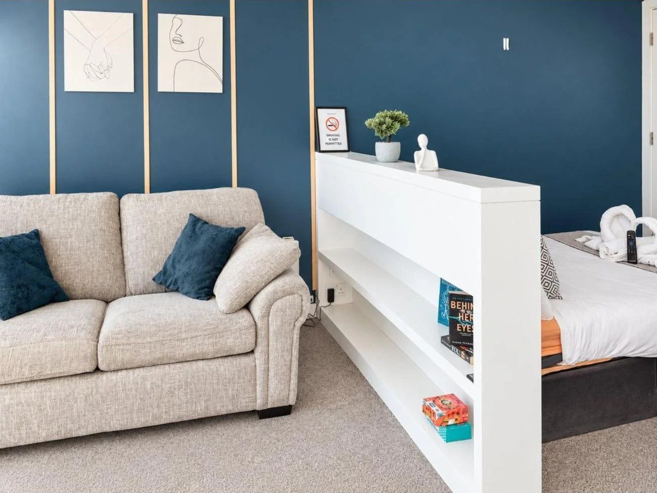 Short-term rental photography Birmingham: open-plan studio layout showing sofa, shelving divider and bed