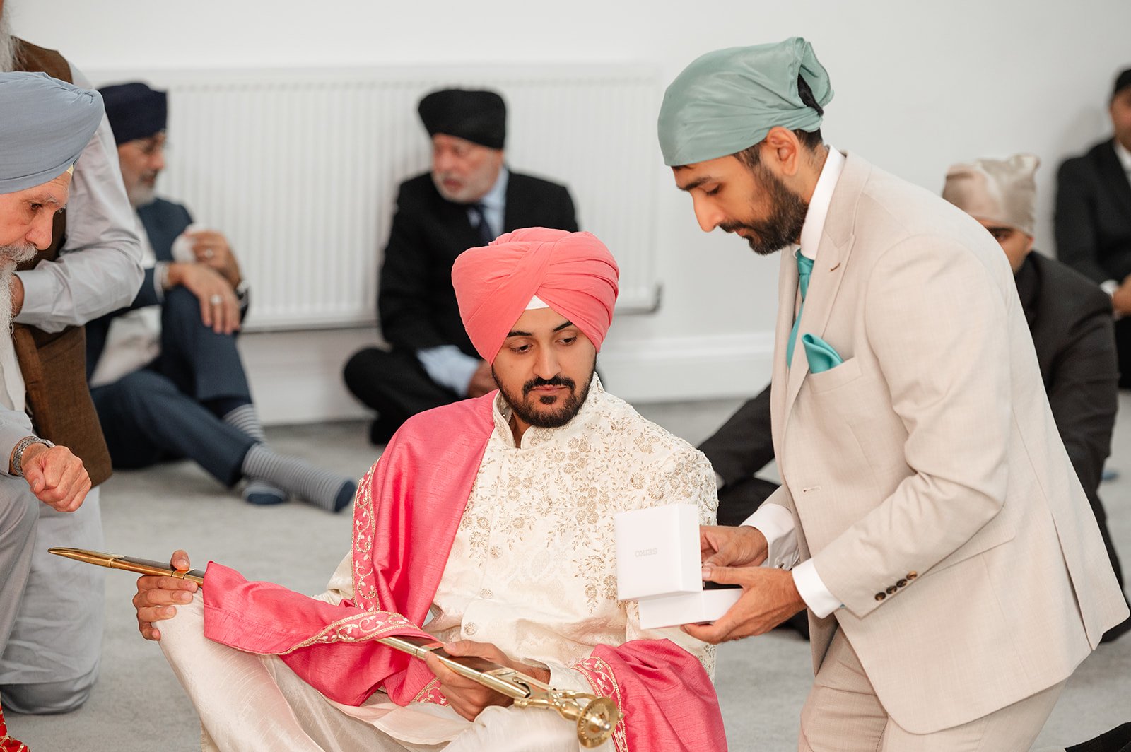 Groom in a pink turban seated with a guest before the Anand Karaj ceremony