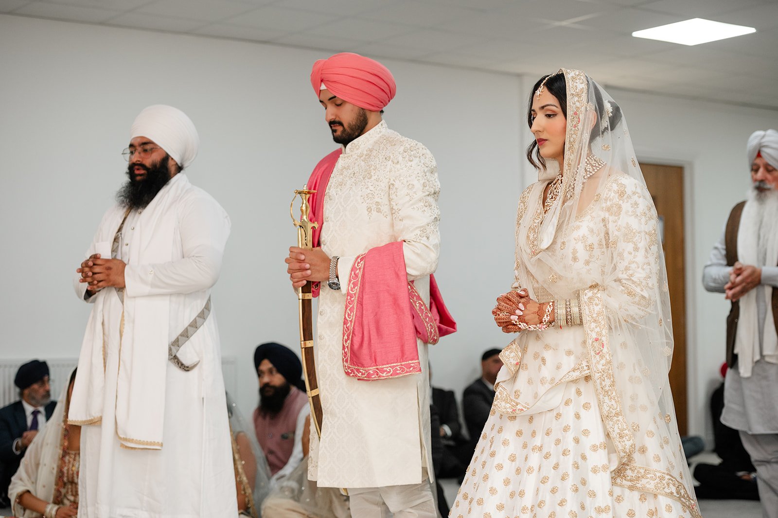 Bride and groom standing together during prayers at their Sikh wedding