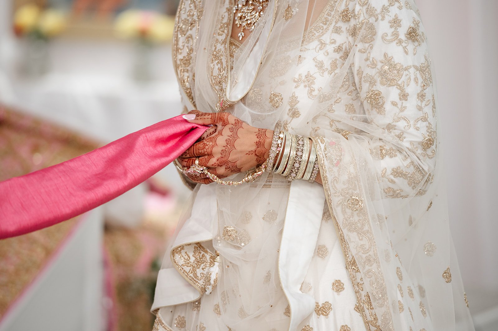 Close-up of the bride’s hands holding the pink wedding scarf