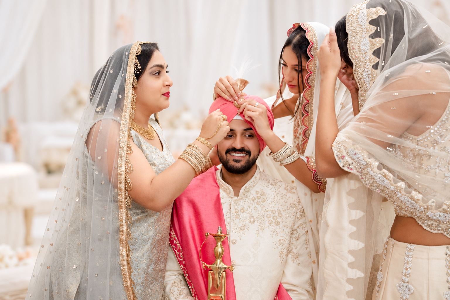 Family adjusting the smiling groom’s pink turban