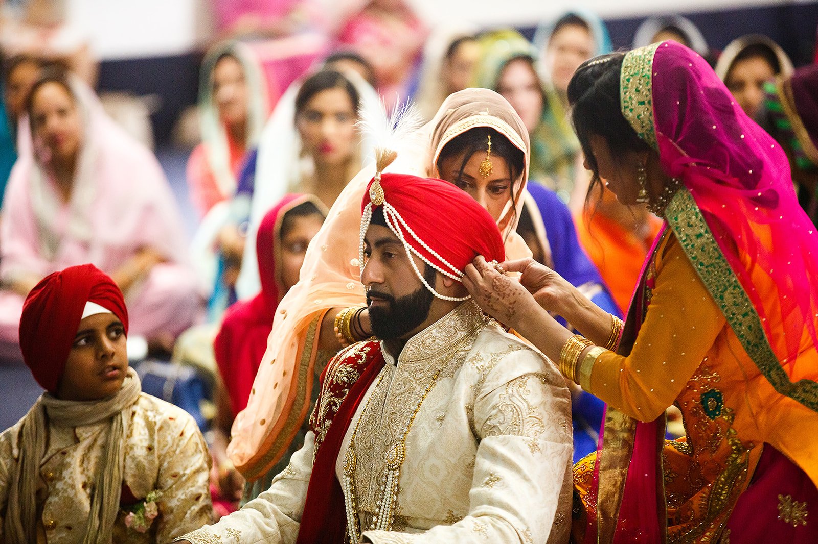 Sikh groom having his traditional wedding turban adjusted during the ceremony