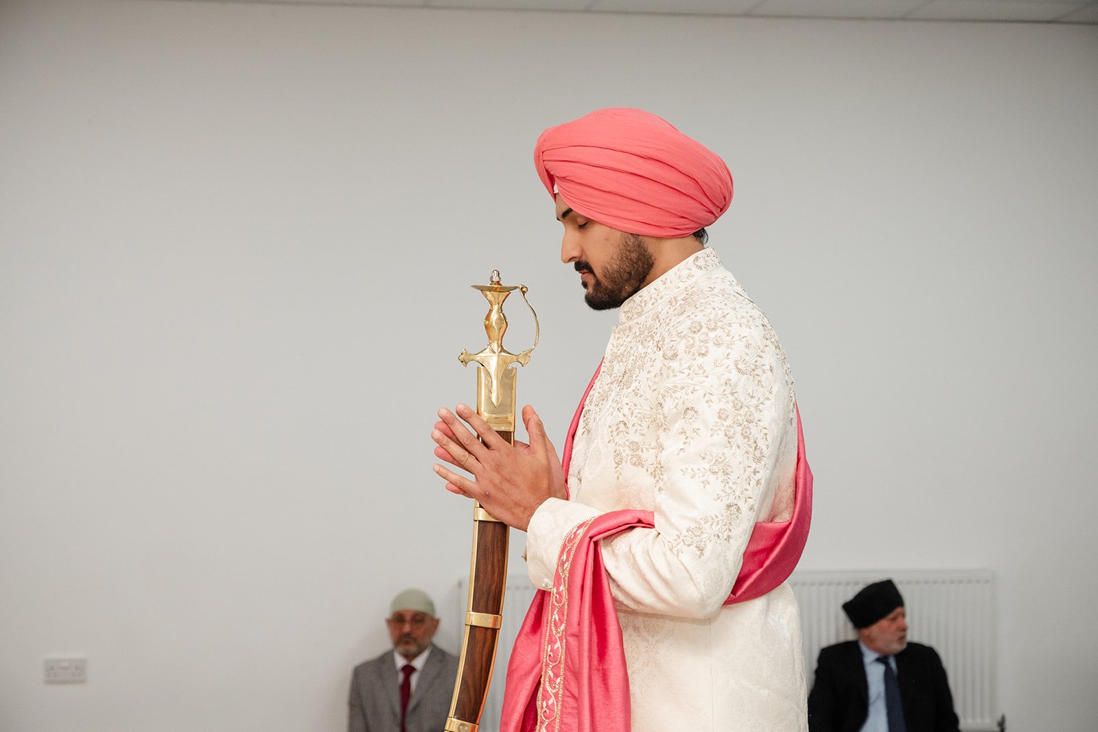 Sikh groom holding his ceremonial sword with hands joined in prayer