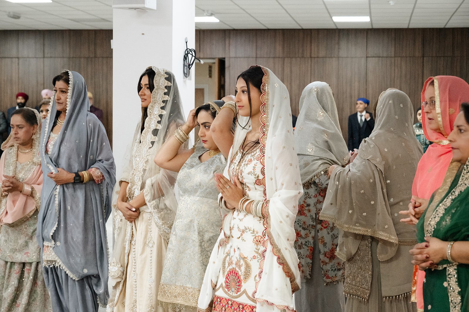 Bride and female wedding guests standing with hands joined in prayer