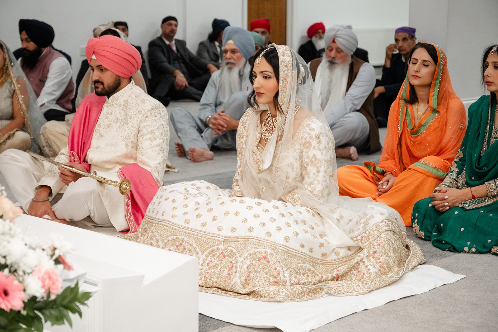 Bride and groom seated with family during their Anand Karaj ceremony